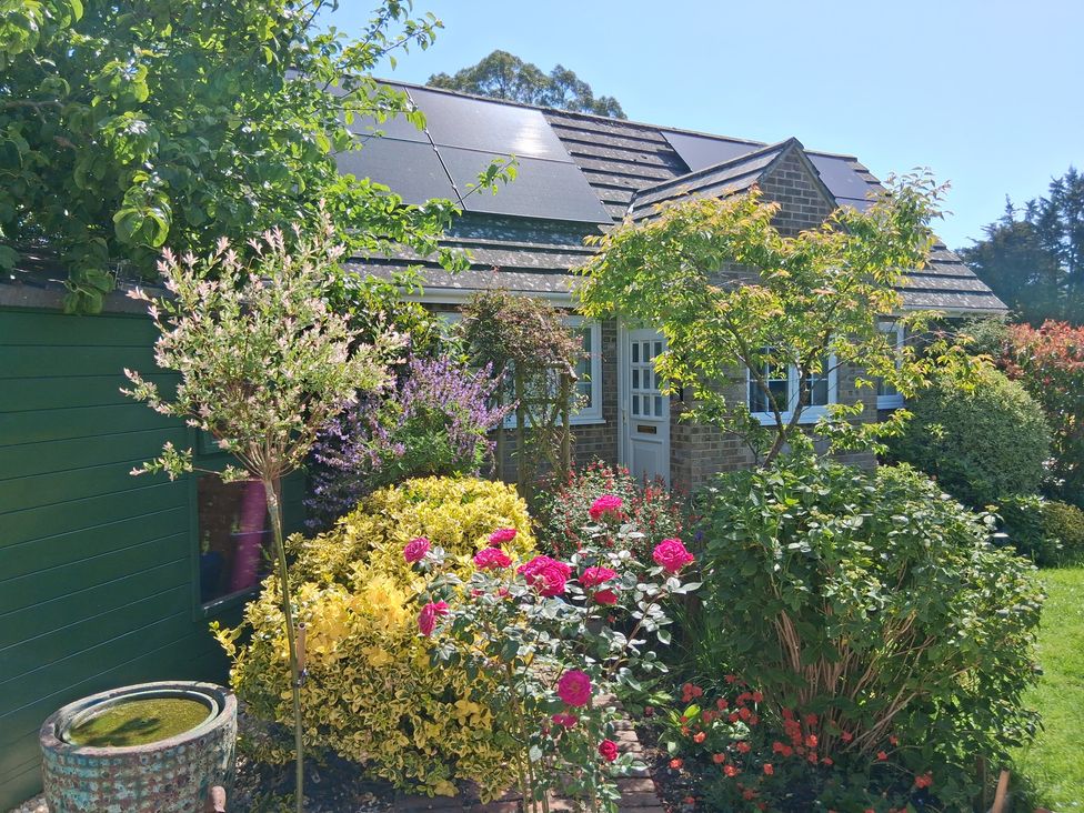 A garden with flowers and a house at Little Retreat in Upwey