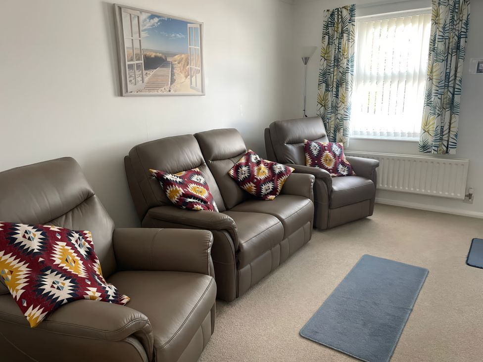 A living room with sofas and cushions at Maisy Cottage in Weymouth