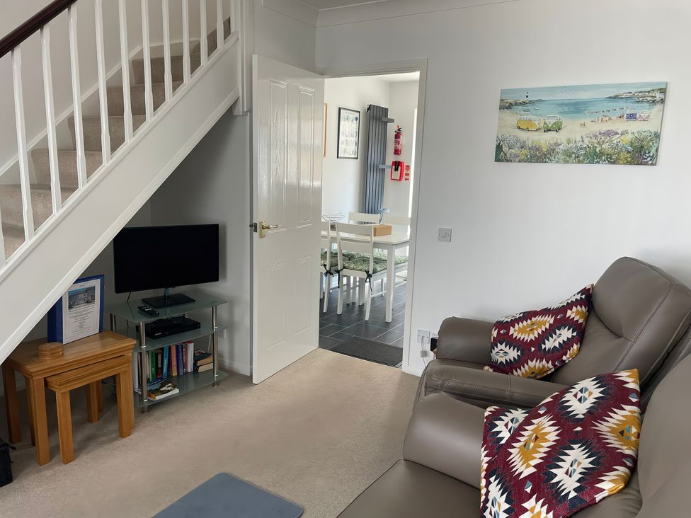 A living room with a television and a staircase at Maisy Cottage in Weymouth