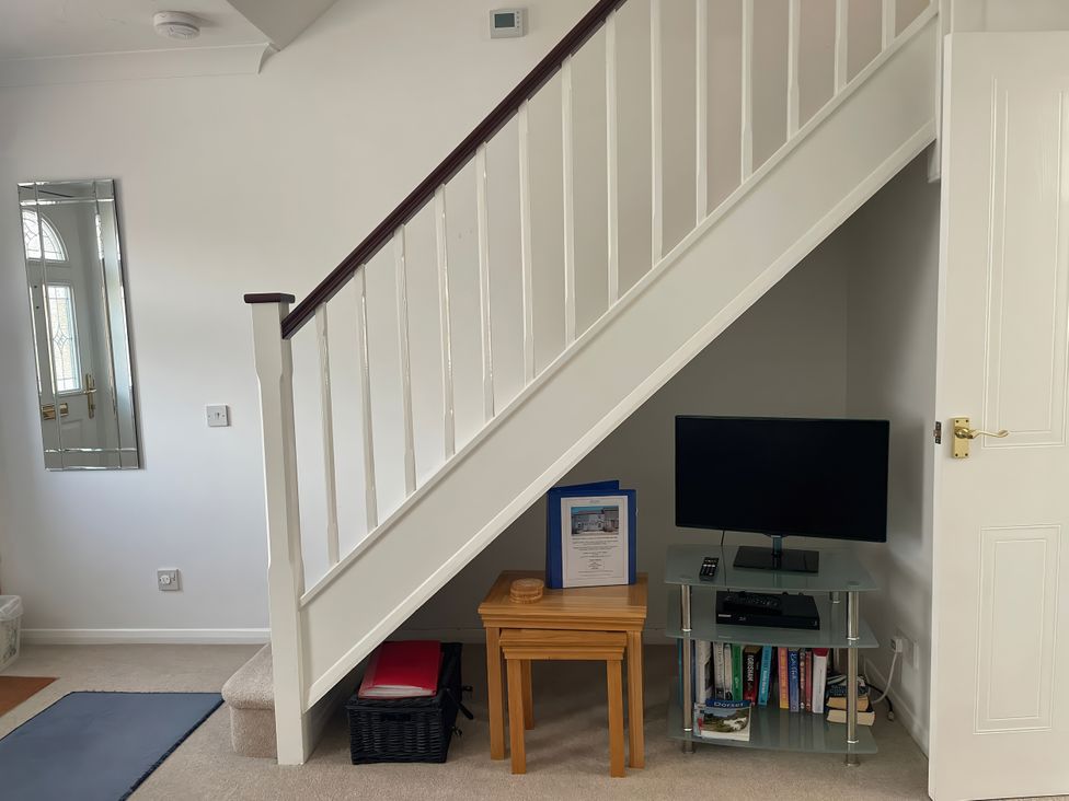 An indoor space featuring stairs, a television, and a table at Maisy Cottage in Weymouth