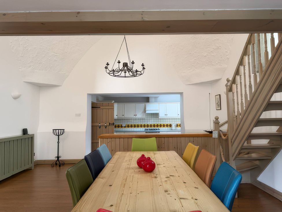 A dining room with a wooden table and colorful chairs at The Oast House in Brewers Quay Harbour