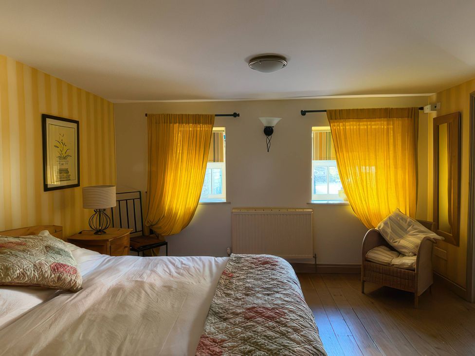 A bedroom with a bed, lamp, and chair at The Oast House in Brewers Quay Harbour