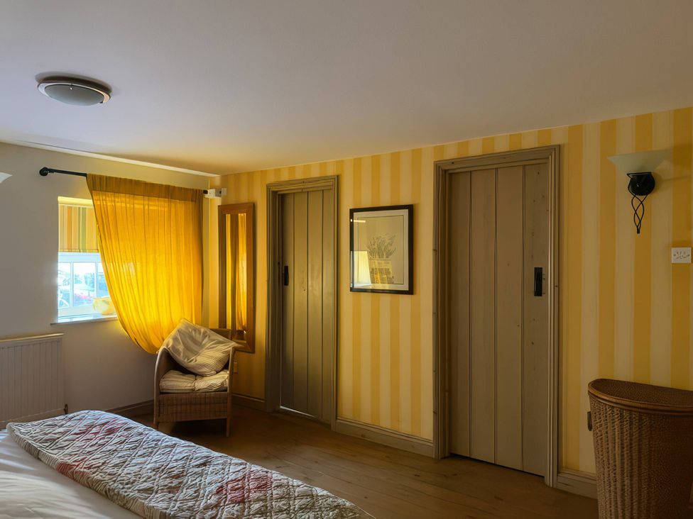 A bedroom with doors and a basket at The Oast House in Brewers Quay Harbour