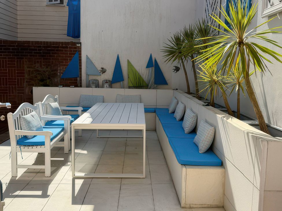 An outdoor seating area with cushioned benches and a dining table at The Oast House in Brewers Quay Harbour