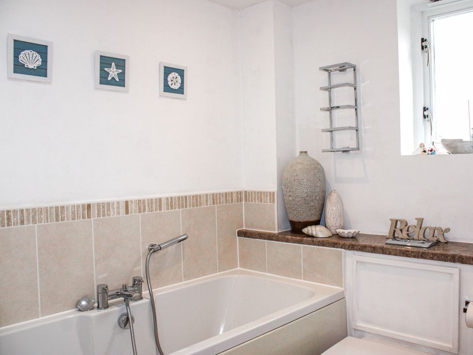 A bathroom with a bathtub and decorative elements at Estuary View in Kingsbridge