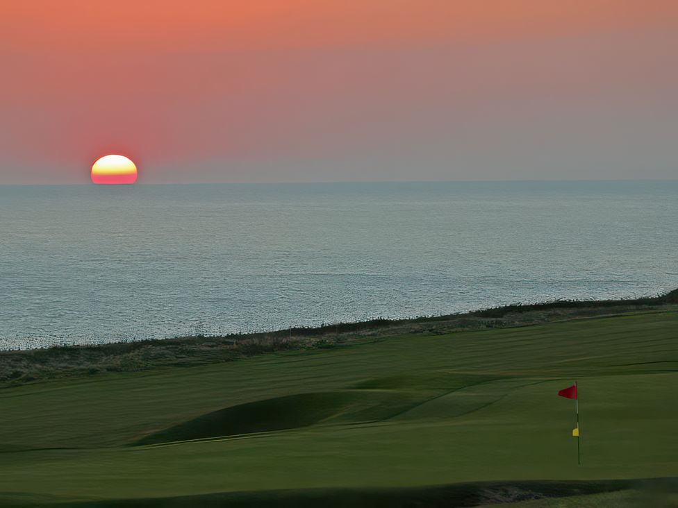 A sunset over the ocean with a golf course at Estuary View Kingsbridge