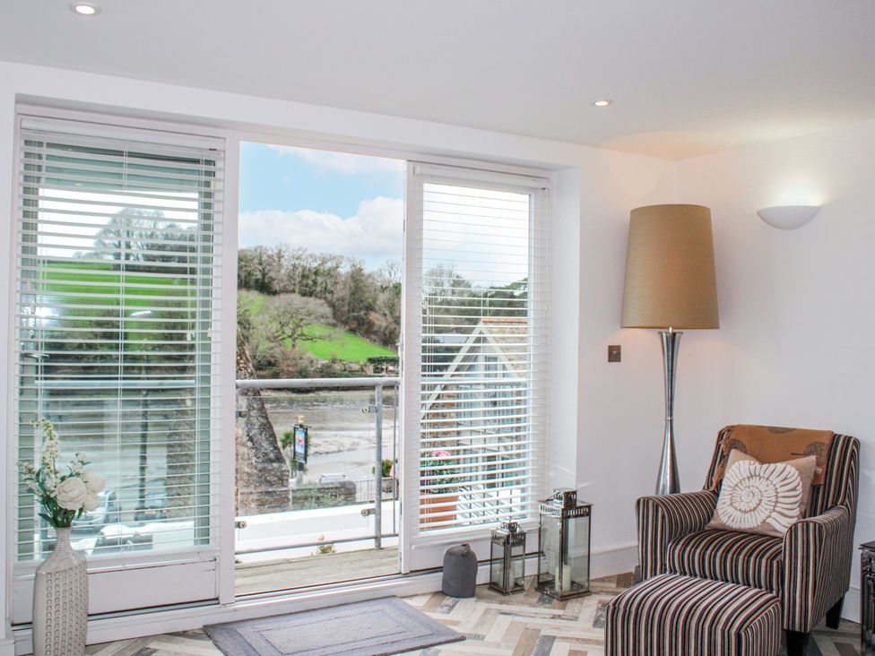 A living room with a chair and large windows at Estuary View in Kingsbridge