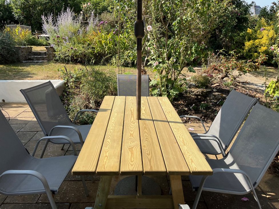 A table with chairs under an umbrella in a garden at Pebbles in Burton Bradstock