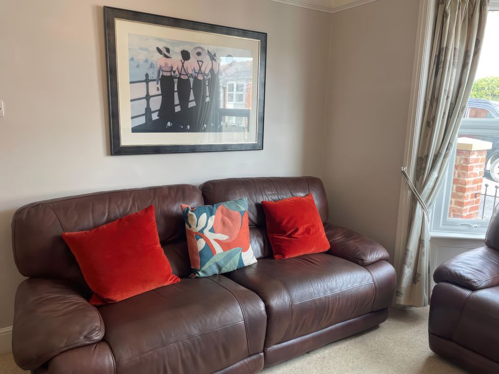 A living room with a brown sofa and wall art at Pedaller's Cottage, Weymouth