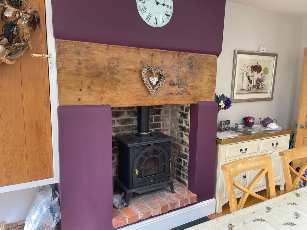 A fireplace with a wooden mantel in a dining room at Pedaller's Cottage in Weymouth