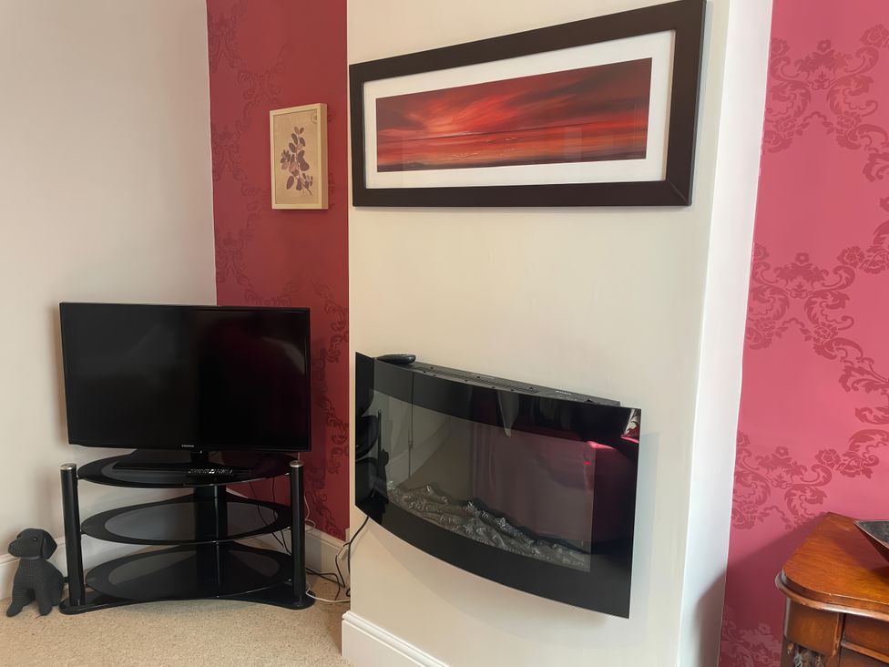 A living room with a television and a fireplace at Pedaller's Cottage in Weymouth