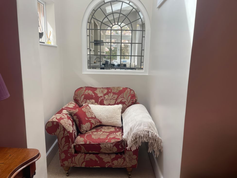 An armchair with a cushion and blanket at Pedaller's Cottage in Weymouth