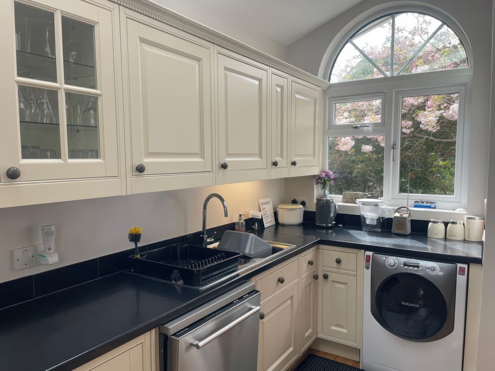 A kitchen with cabinets, sink and washing machine at Pedaller's Cottage in Weymouth