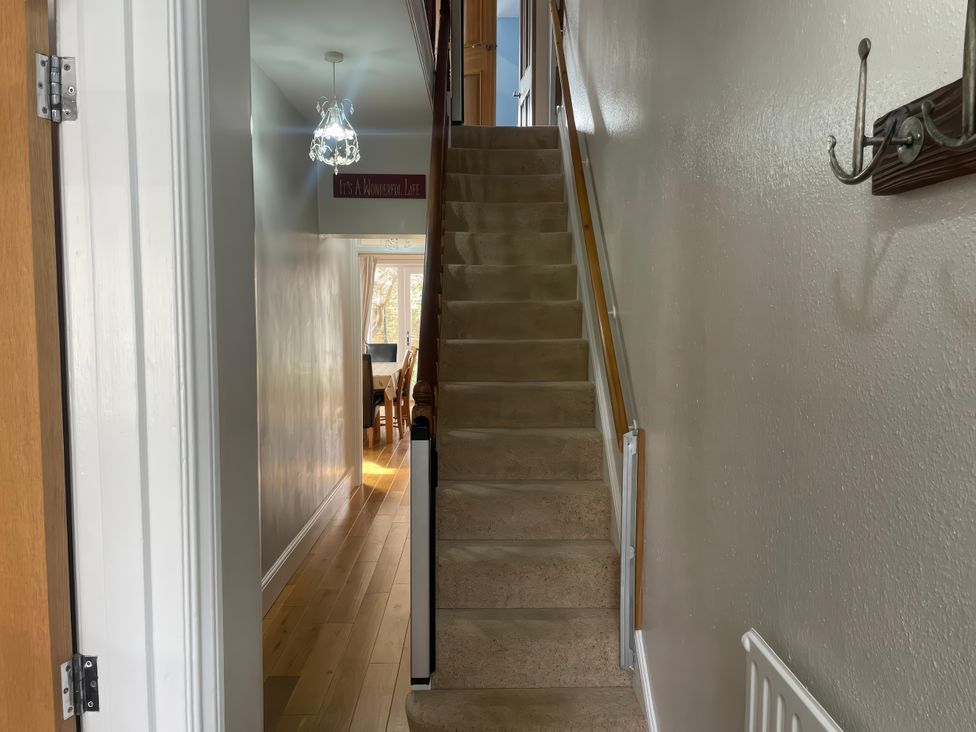 A hallway with a staircase and light fixture at Pedaller's Cottage in Weymouth