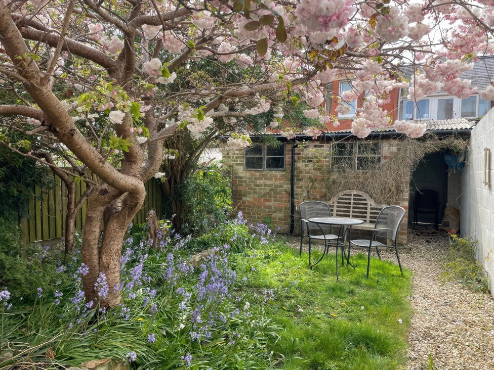 A garden with a table and chairs under a flowering tree at Pedaller's Cottage in Weymouth