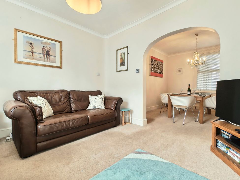 A living room with a sofa and dining area at Quay Cottage Weymouth