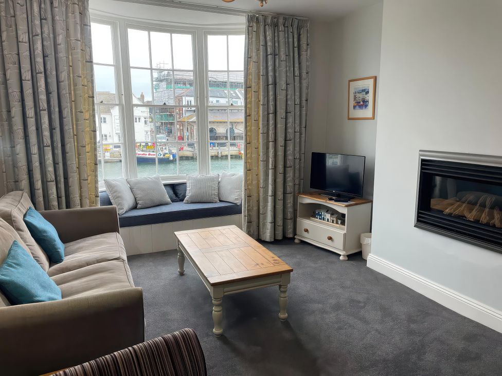 A living room with a sofa, television, and coffee table at Safe Harbour in Brewers Quay harbour