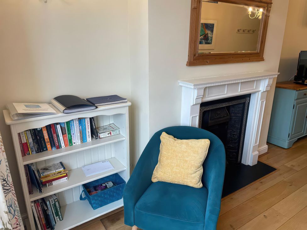 A living room with a bookshelf and blue chair at Safe Harbour in Brewers Quay harbour