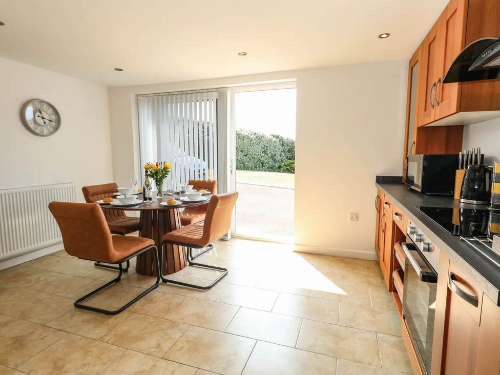 A kitchen with a dining area and sliding doors at Tides Corner in Bowleaze