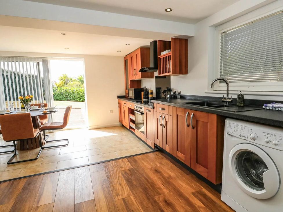 A kitchen with a dining table and washing machine at Tides Corner in Bowleaze