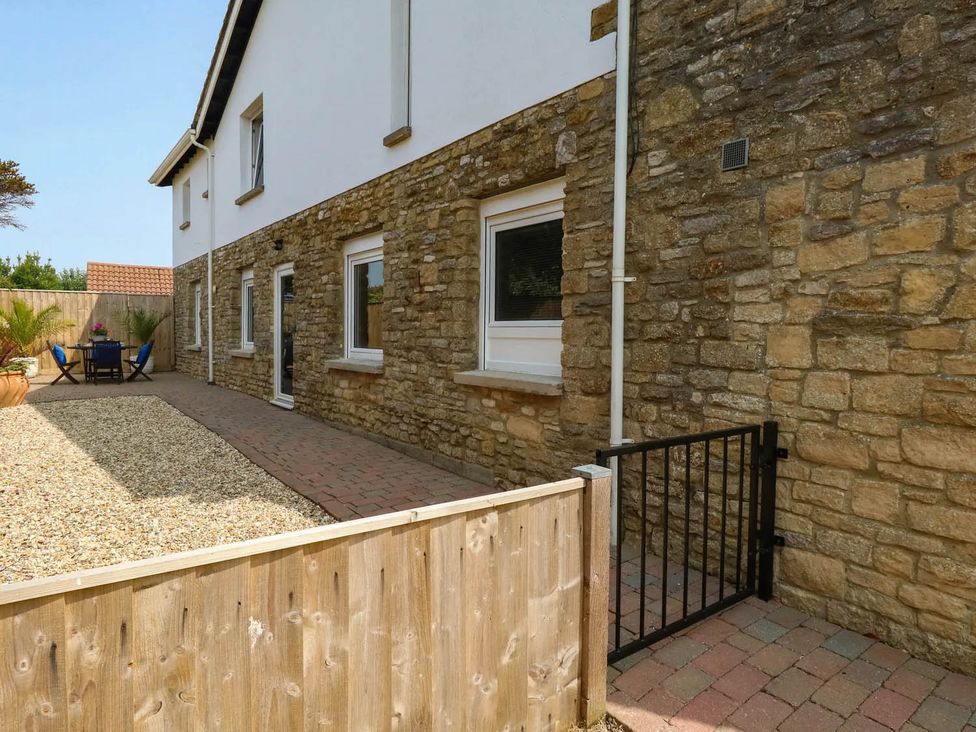 An outdoor area with a stone wall, seating, and gravel at Tides Corner in Bowleaze