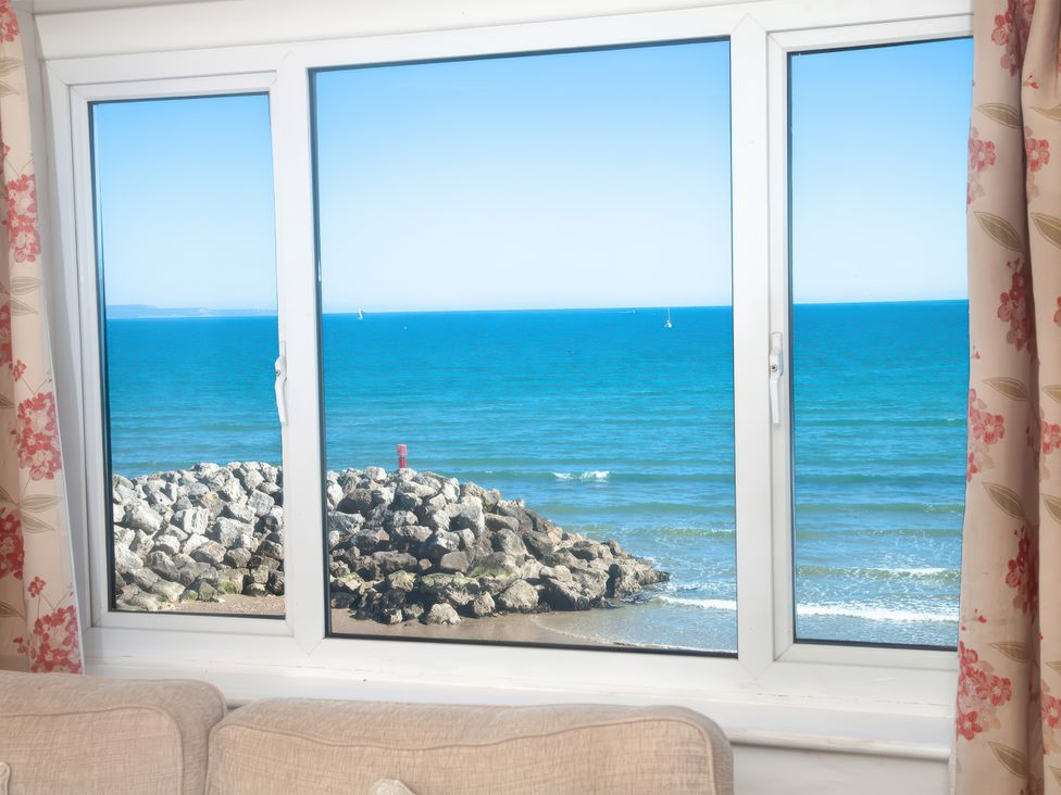 A view of the ocean and rocks through a window at Weymouth Bay Apartment C in Greenhill