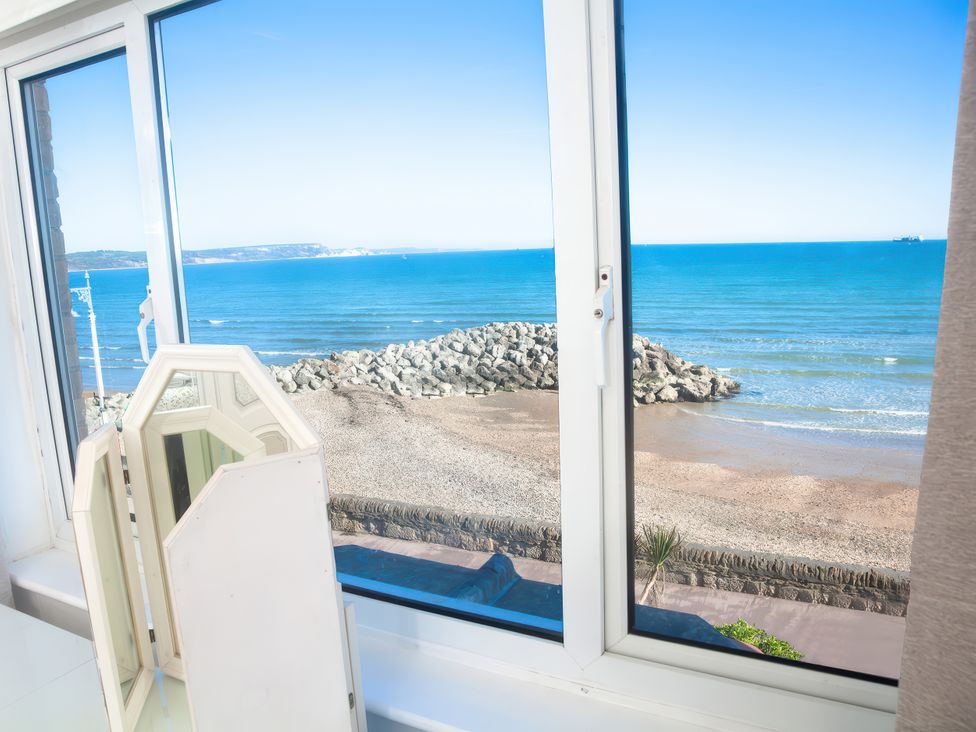 A view from a window showing the beach and ocean at Weymouth Bay Apartment C in Greenhill