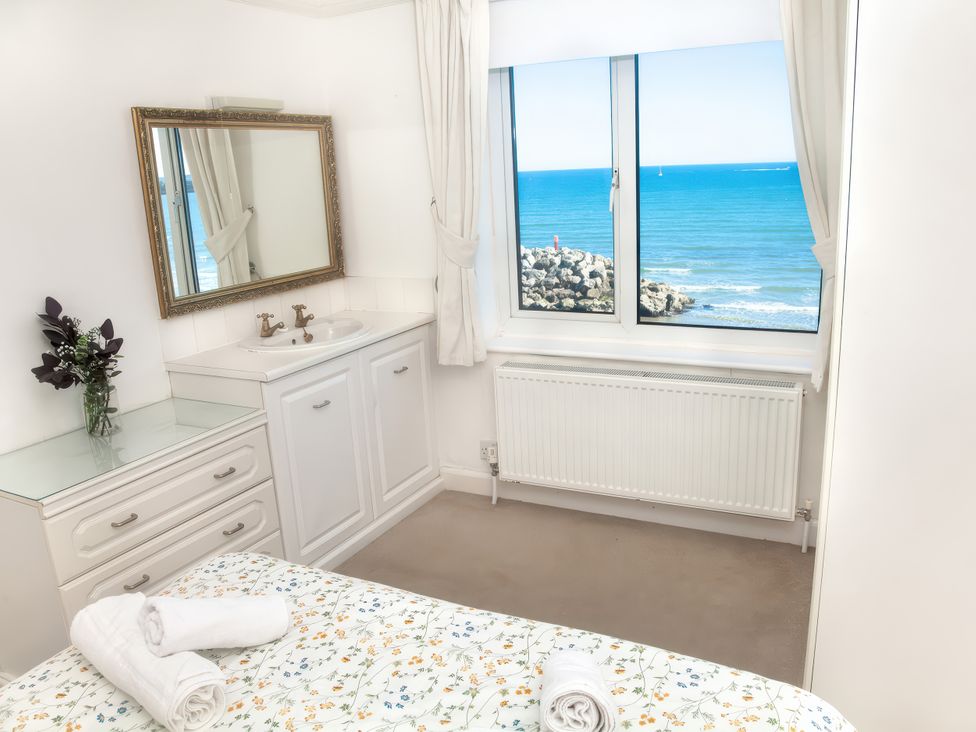 A bedroom with a bed and a dressing table at Weymouth Bay Apartment C in Greenhill