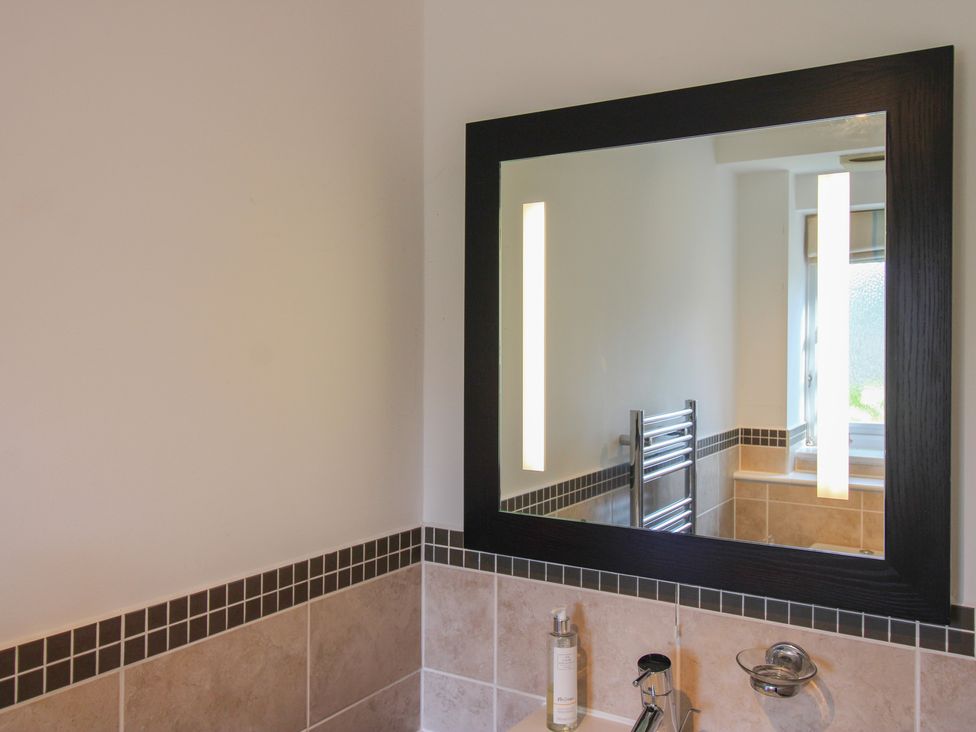 A bathroom with a mirror and towel radiator at 16 Bolt Head Salcombe