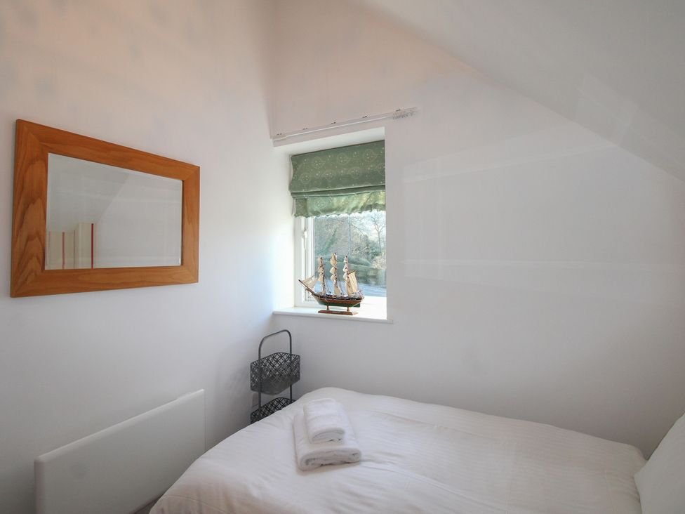 A bedroom with a bed, mirror, window and ship model at 16 Bolt Head in Salcombe