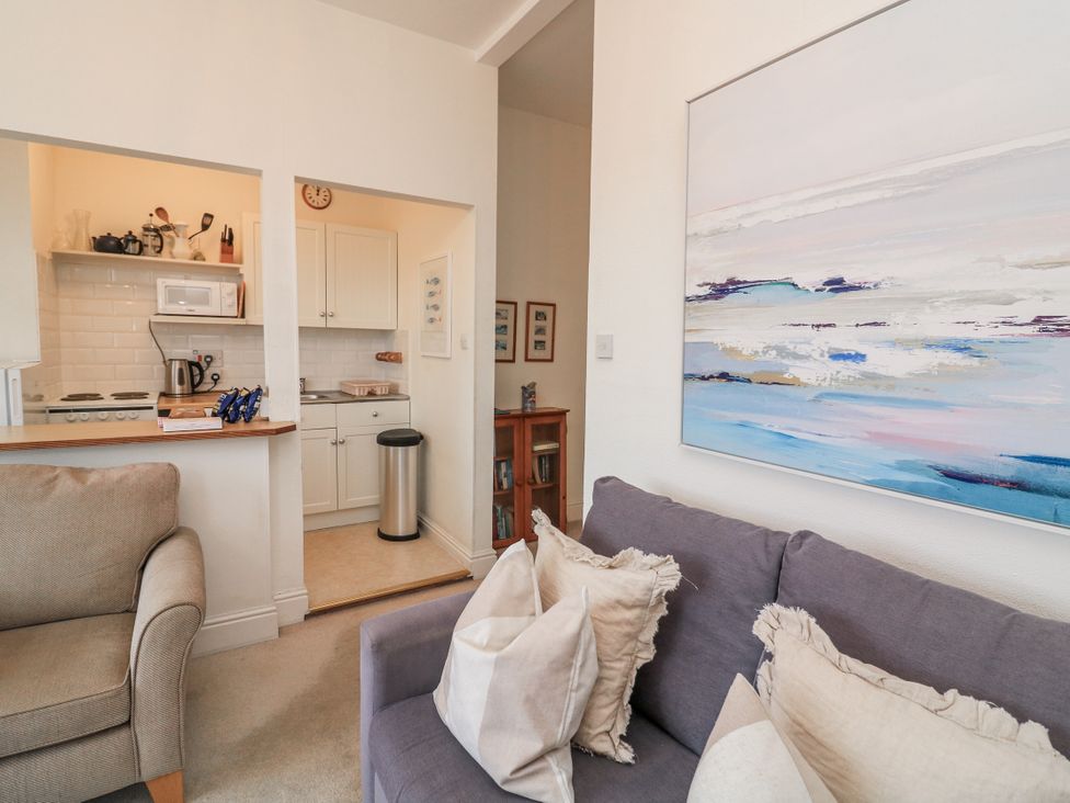 A living room with a sofa and kitchen area at 1 Hazeldene Salcombe