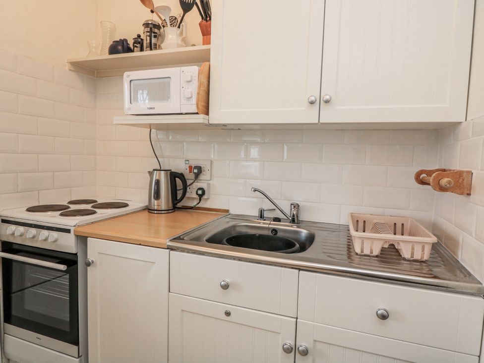 A kitchen with a sink, stovetop, and microwave at 1 Hazeldene in Salcombe