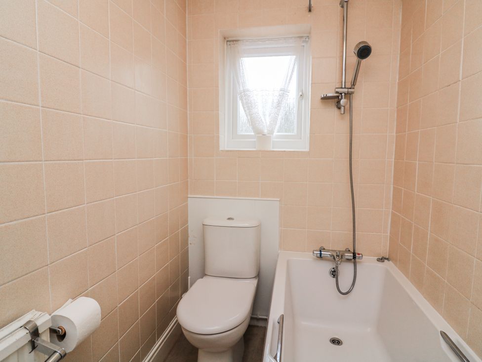 A bathroom with a bathtub and toilet at 1 Hazeldene in Salcombe