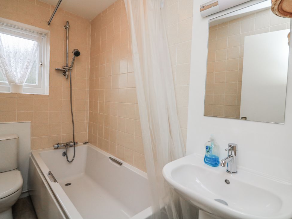 A bathroom with a bathtub, toilet, sink and mirror at 1 Hazeldene Salcombe