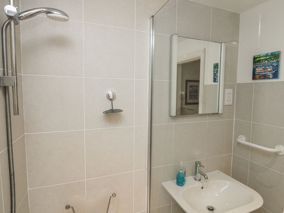 A bathroom with a shower, sink, and mirror at 1 Hazeldene in Salcombe