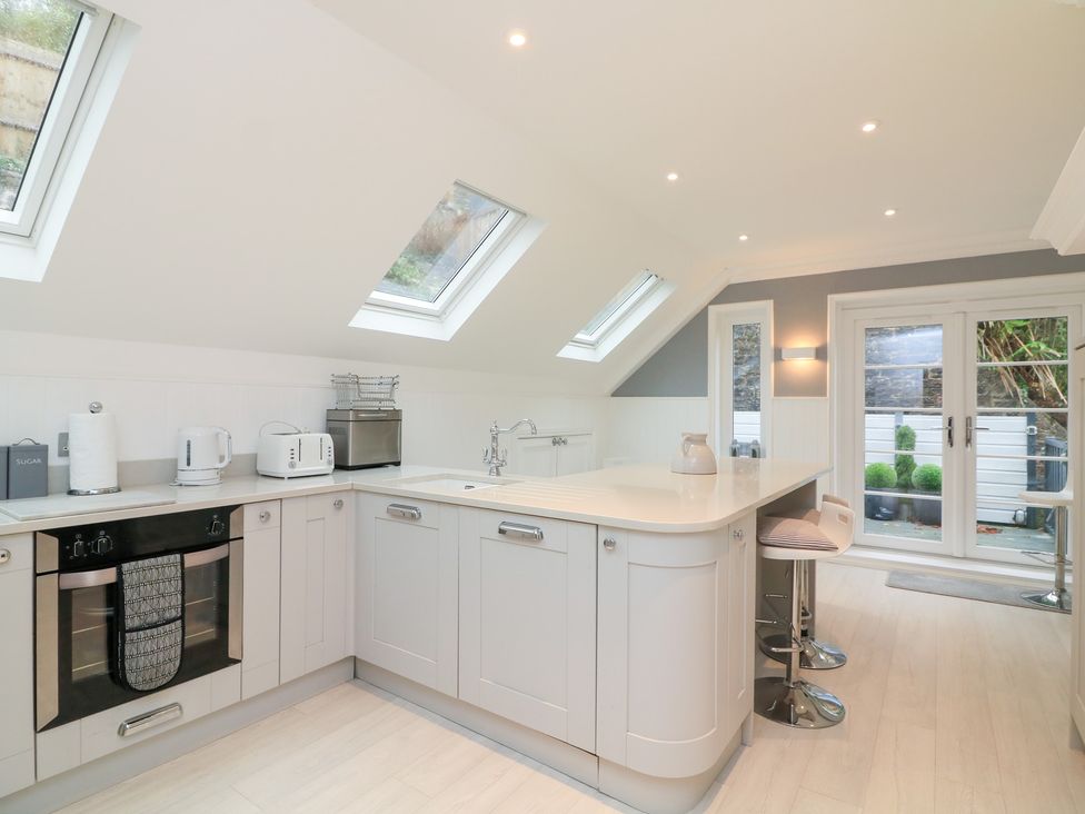 A kitchen with appliances and bar stools at 1 The Old Coach House Dartmouth