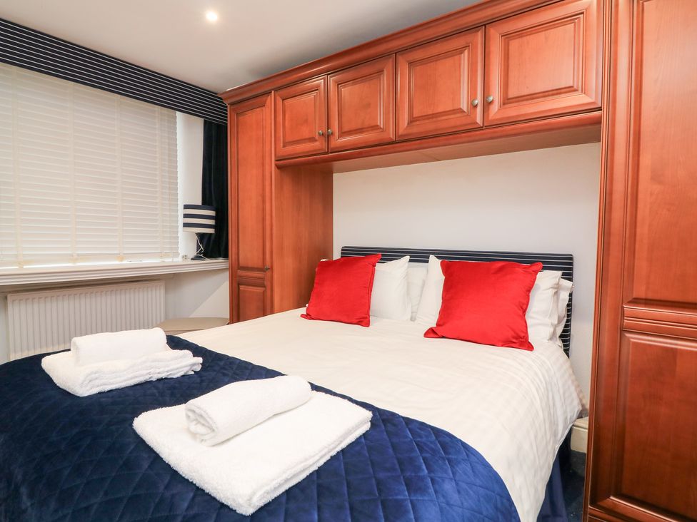 A bedroom with a bed and wardrobe at 1 The Old Coach House in Dartmouth