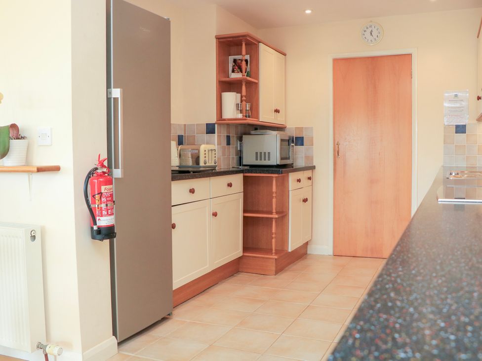 A kitchen with a refrigerator microwave toaster fire extinguisher cabinets and a door at 2 Sea Gardens in Hope Cove