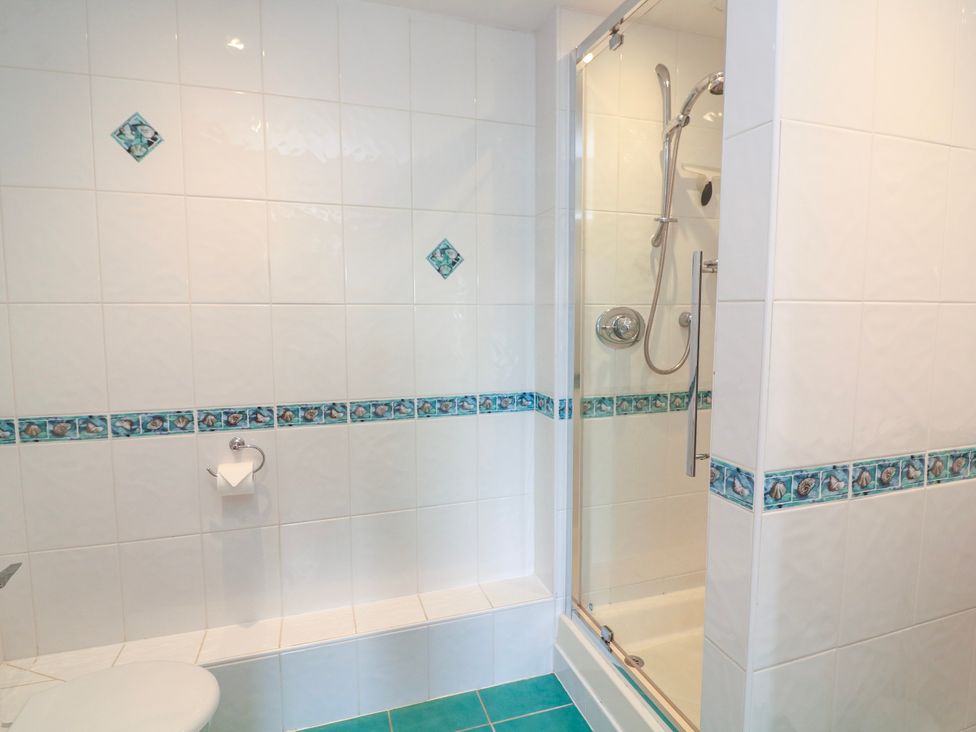 A bathroom with tiled walls and a shower enclosure at 2 Sea Gardens in Hope Cove