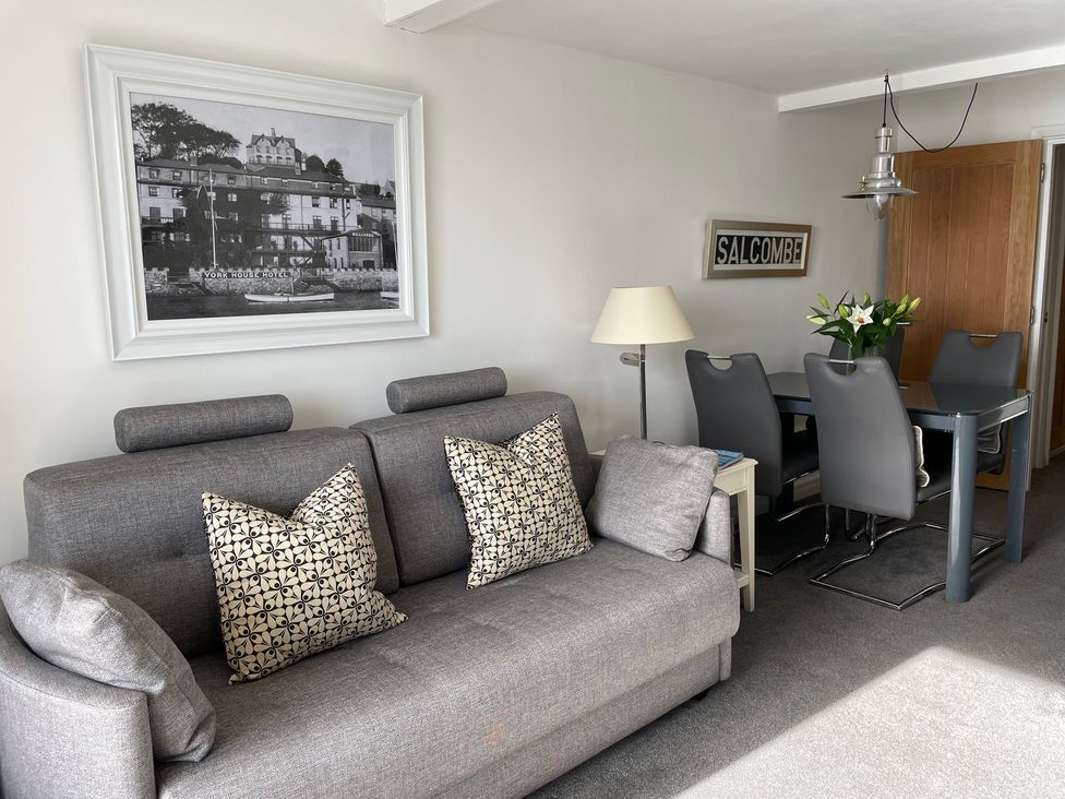 A living room with a sofa and dining area at 35 The Salcombe in Salcombe