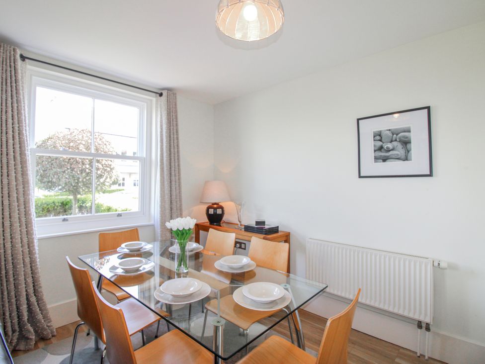 A dining room with a glass table and chairs at 3 Combehaven in Salcombe