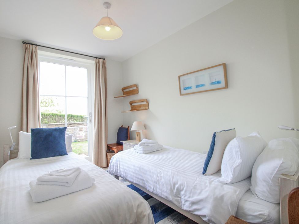 A bedroom with two beds and a window at 3 Combehaven Salcombe
