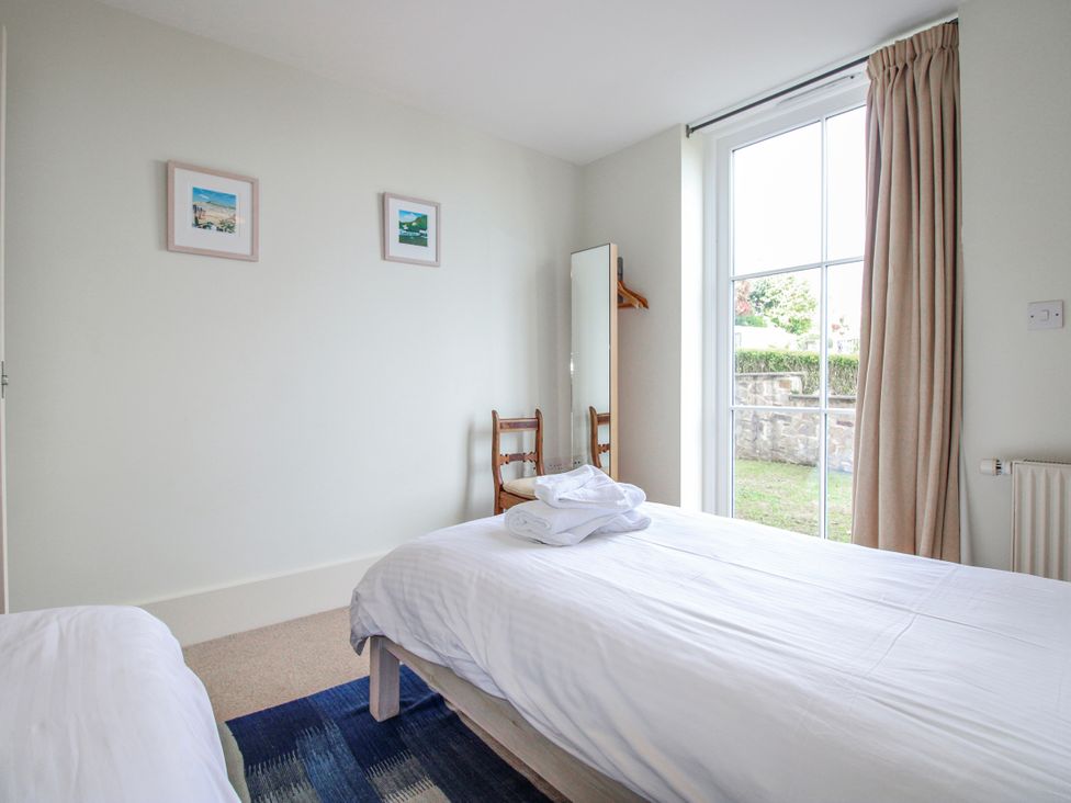 A bedroom with two beds and a chair at 3 Combehaven in Salcombe