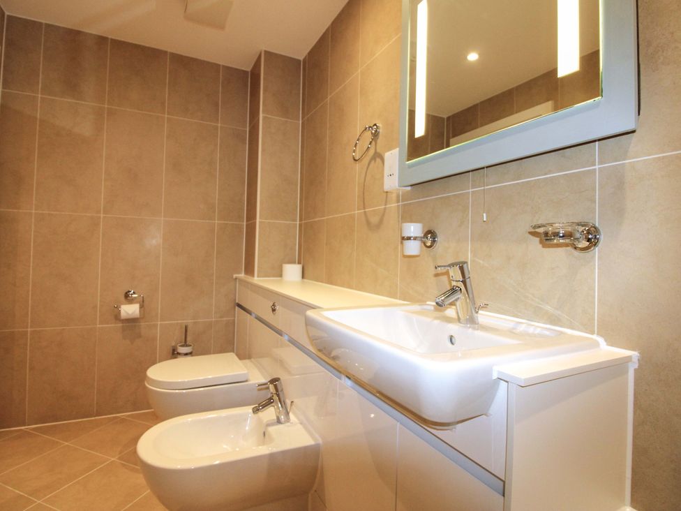 A bathroom with sink, toilet, bidet and mirror at 4 Bolt Head in Salcombe