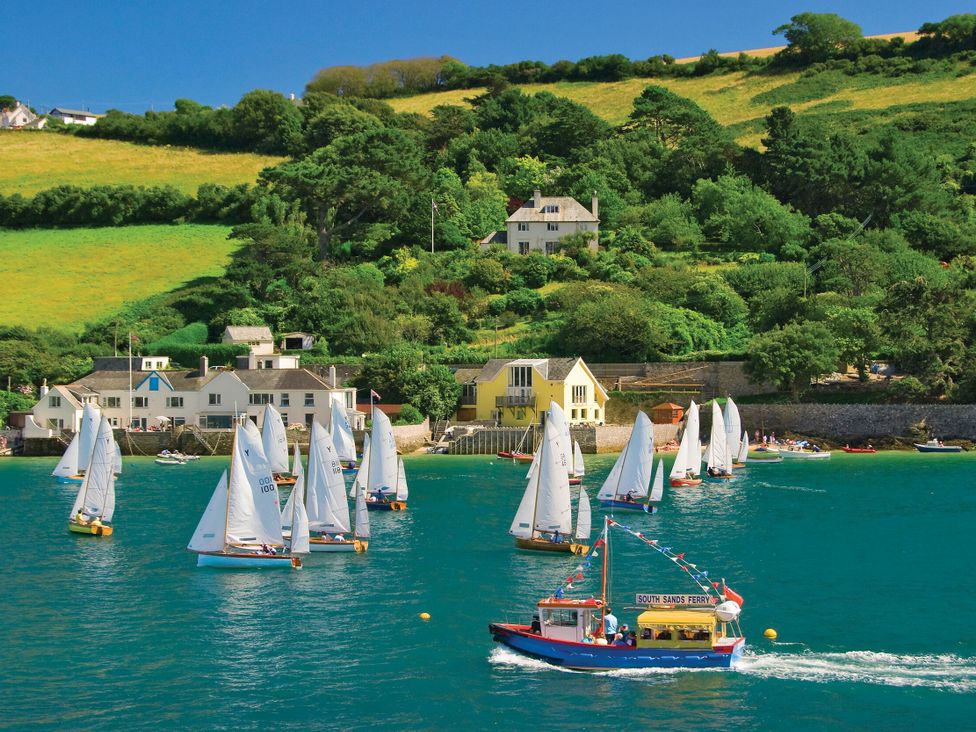 Sailboats and a ferry boat in water with houses and hills in the background at 6 Combehaven Salcombe