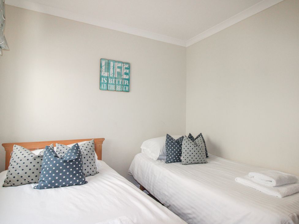 A bedroom with two beds and decorative pillows at 7 Thurlestone Rock in Thurlestone
