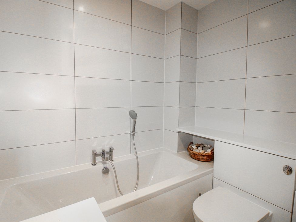 A bathroom with a bath tub and toilet at 7 Thurlestone Rock in Thurlestone