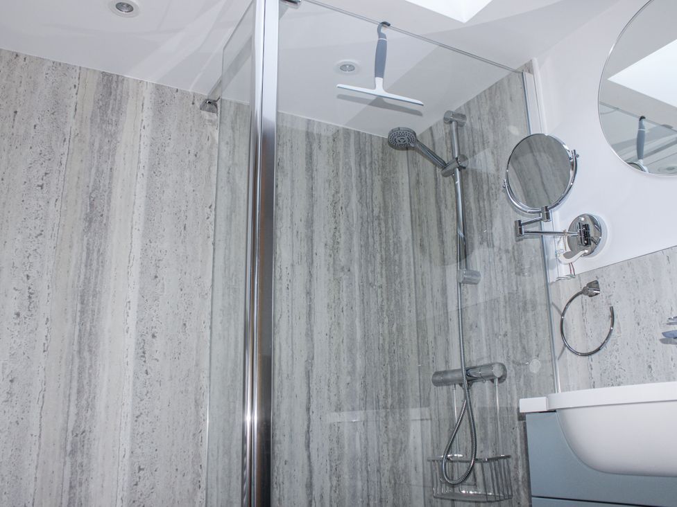 A shower with glass door and wall panel at Armada Cottage Dartmouth