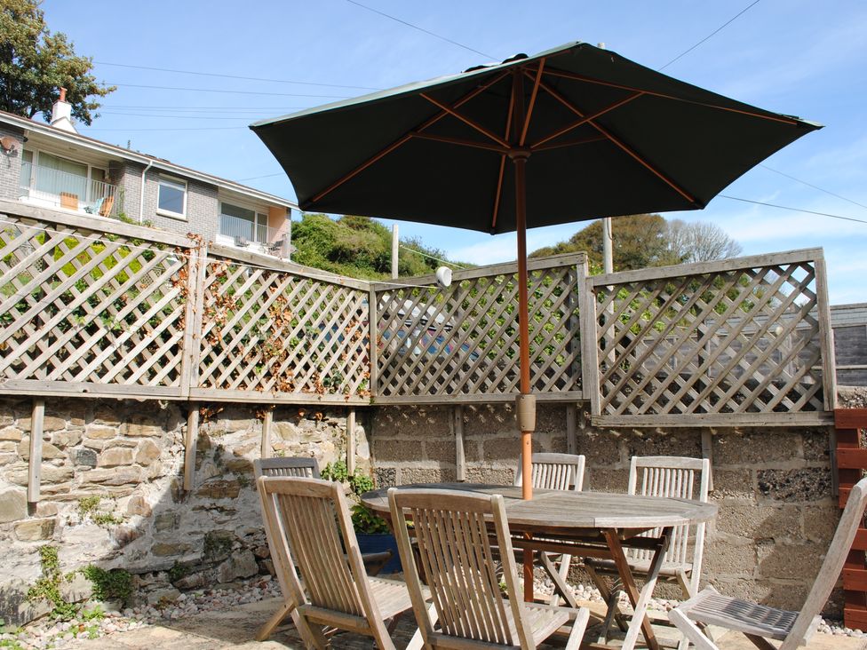 An outdoor area with a table and chairs under an umbrella at Crab Cottage Salcombe