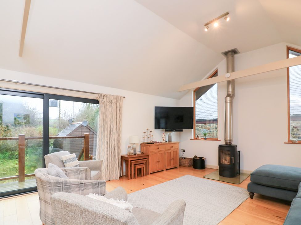 A living room with a television and wooden stove at Courtyard Cottage in Dartmouth